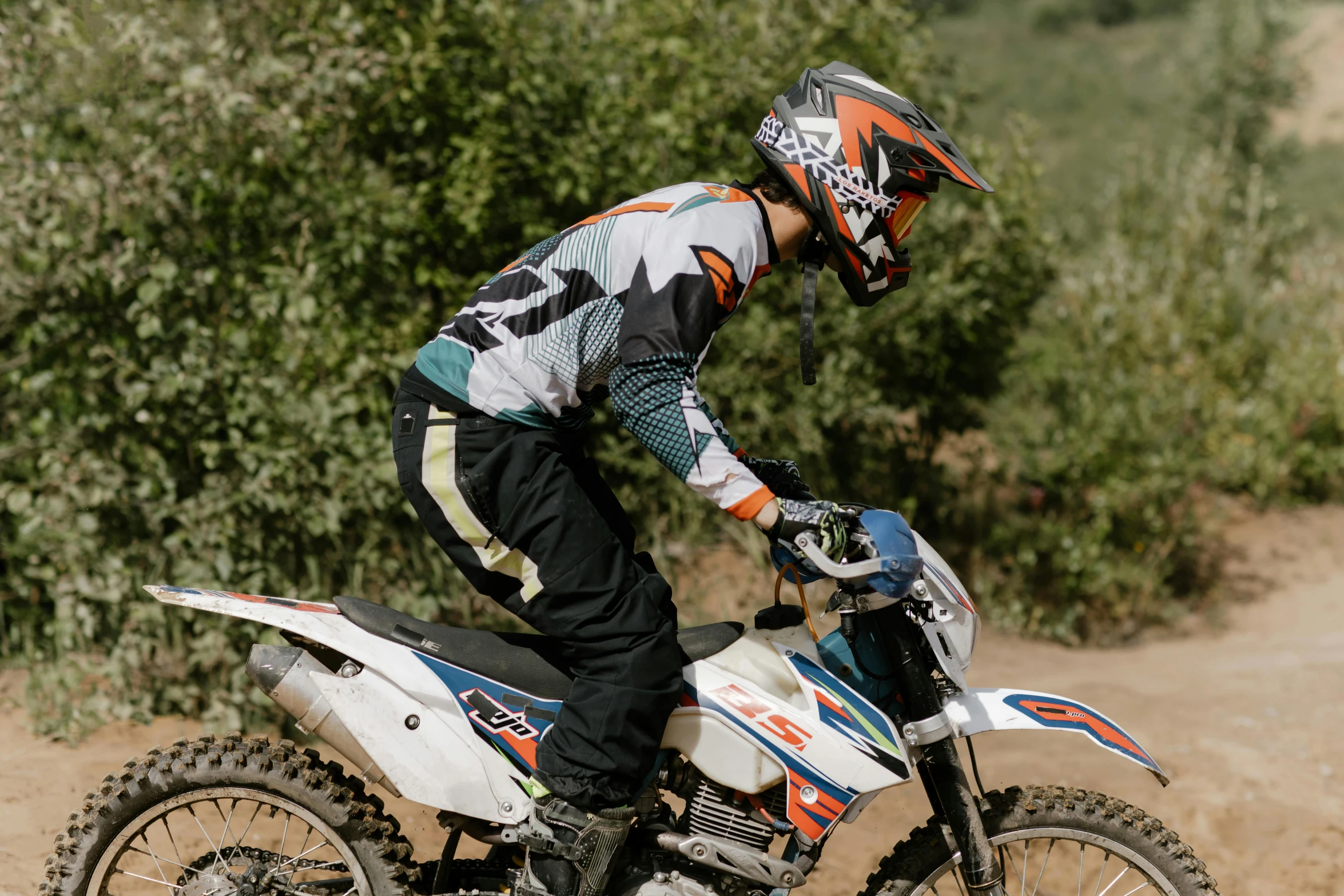 a person riding a dirt bike on a dirt road, profile image, sports clothing, multicoloured, mateo dineen