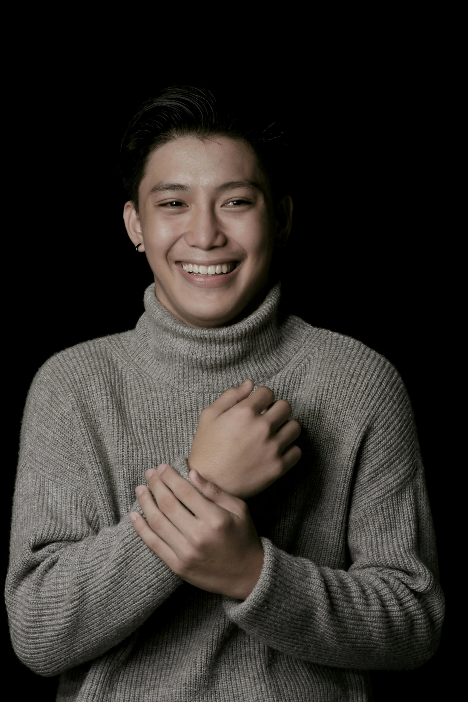 a man in a turtle neck sweater posing for a picture, an album cover, inspired by Joong Keun Lee, sumatraism, warm and gentle smile, on a black background, instagram picture, he is wearing a brown sweater