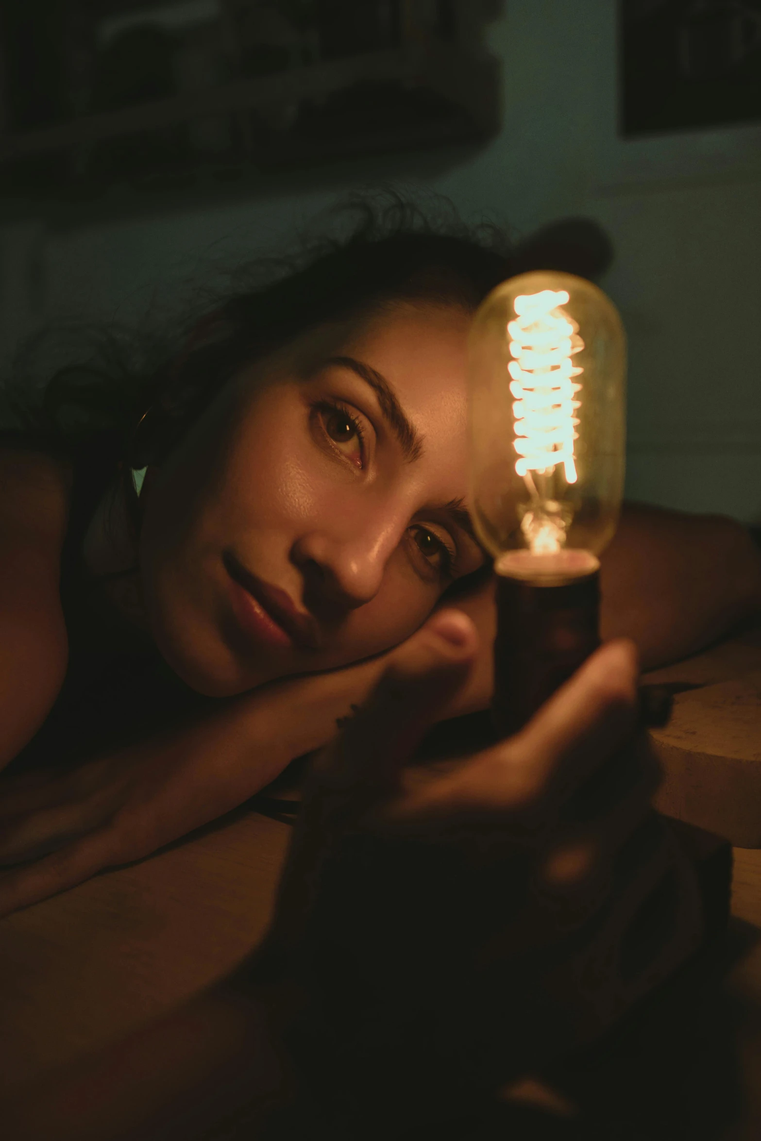 a woman laying on a bed next to a light bulb, inspired by Elsa Bleda, pexels contest winner, closeup portrait, reflecting, low quality photo, nixie tubes