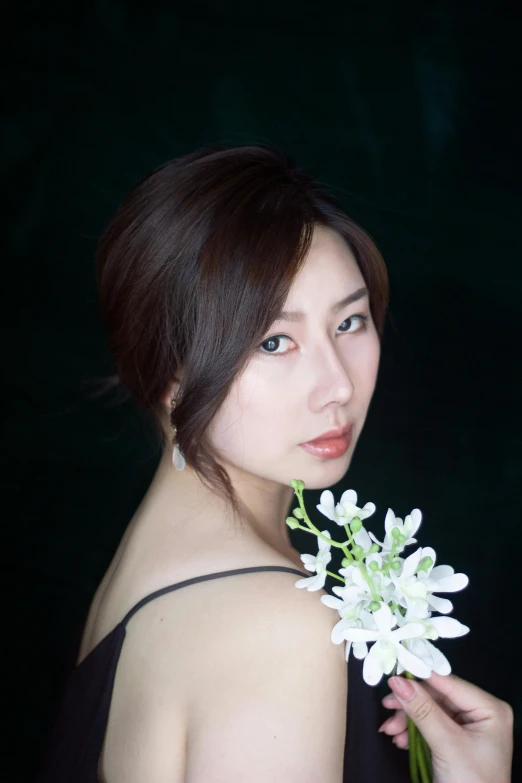 a woman in a black dress holding a white flower, an album cover, inspired by Kim Du-ryang, headshot and bodyshot, looking towards camera, professional photo-n 3, square