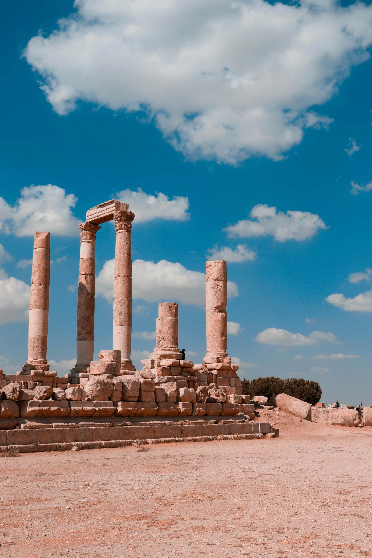 a group of pillars sitting on top of a dirt field, a marble sculpture, pexels contest winner, neoclassicism, blue skies, jordan, examining ruins, alexandria\'s genesis