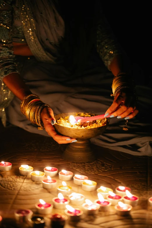 a woman holding a bowl filled with lit candles, pexels contest winner, hurufiyya, lamps on ground, indian art, on location, decorations