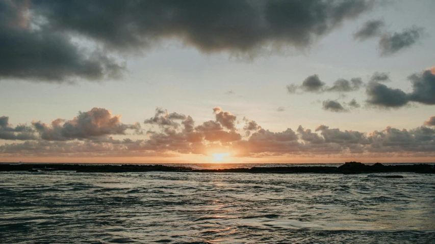 the sun is setting over a body of water, unsplash, kauai, view from the sea, humid evening, flattened
