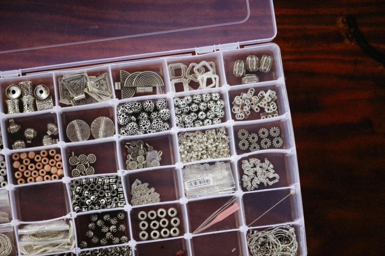 a box filled with lots of different types of beads, by Alison Watt, pexels, assemblage, silver filigree details, white and silver, modular, product introduction photo