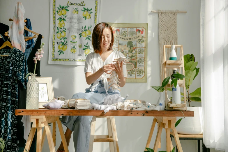 a woman sitting on top of a wooden table, inspired by Kim Du-ryang, trending on pexels, process art, presenting wares, home display, sitting at a desk, small manufacture