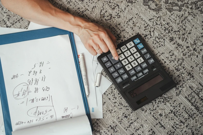 a calculator sitting on top of a pile of papers, by Julia Pishtar, pexels, holding notebook, flat lay, multiple stories, 15081959 21121991 01012000 4k