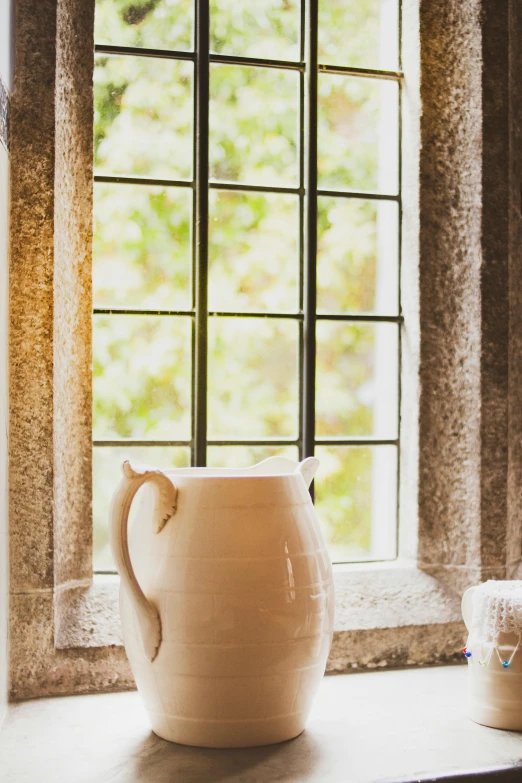 a white pitcher sitting on top of a window sill, arts and crafts movement, in a monestry natural lighting, promo image, lush surroundings, bathed in light