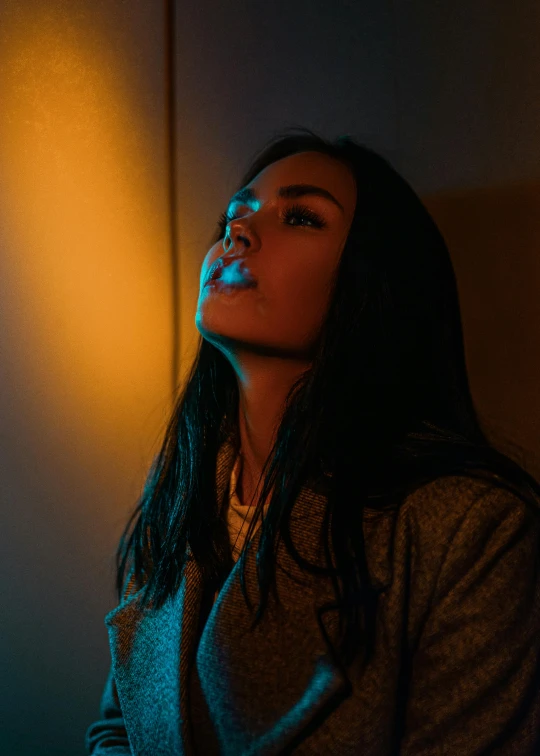 a woman standing in a dimly lit room, inspired by Elsa Bleda, trending on pexels, cigarette in mouth, orange and cyan lighting, young asian woman, instagram post