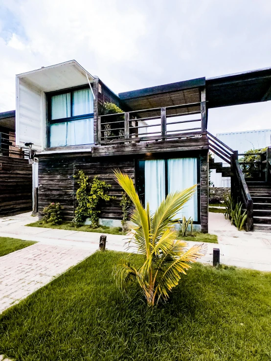 a house sitting on top of a lush green field, black vertical slatted timber, in a beachfront environment, thumbnail, apartment