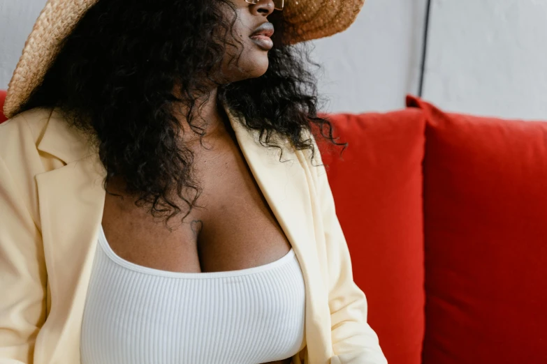 a woman sitting on a couch wearing a hat, trending on pexels, white bra, ebony skin, revealing outfit, afternoon hangout