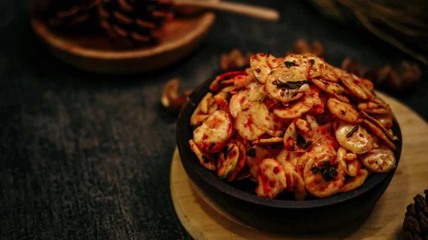 a bowl of food sitting on top of a wooden table, pizza cosmos, squids, with a black dark background, crisps