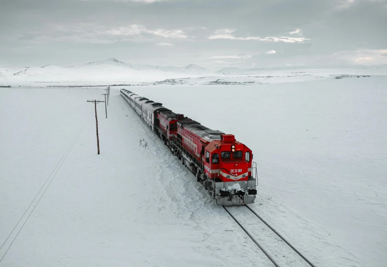 a large long train on a steel track, by Brian Snøddy, pexels contest winner, snowy arctic environment, crimson themed, thumbnail, grey