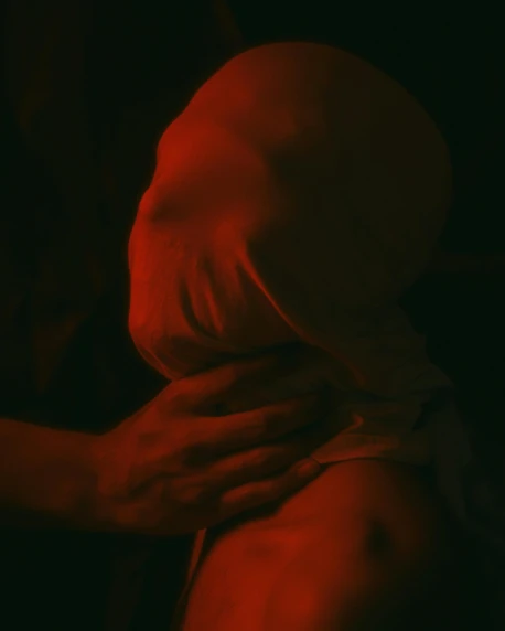 a woman standing in front of a red light, a statue, inspired by Hans Bellmer, unsplash, transgressive art, two men hugging, still from film, red-fabric, in a dark