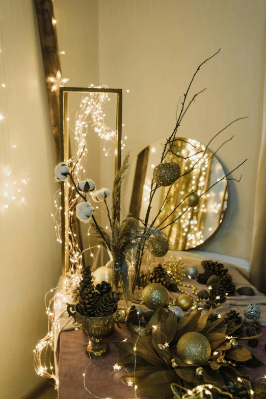 a mirror sitting on top of a table next to a mirror, light and space, christmas lights, botanicals, angled shot, gold trimmings