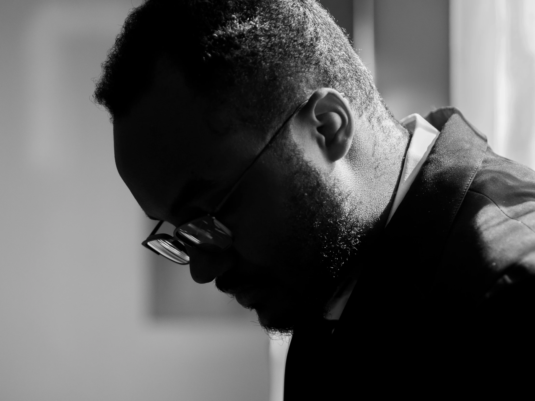 a black and white photo of a man with glasses, a black and white photo, inspired by Theo Constanté, head bowed slightly, riyahd cassiem, contemplating, profile image