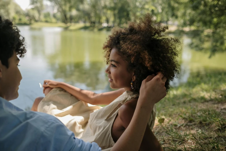 a man and a woman sitting next to each other, pexels contest winner, natural hair, parks and lakes, tiny girl looking on, she has olive brown skin