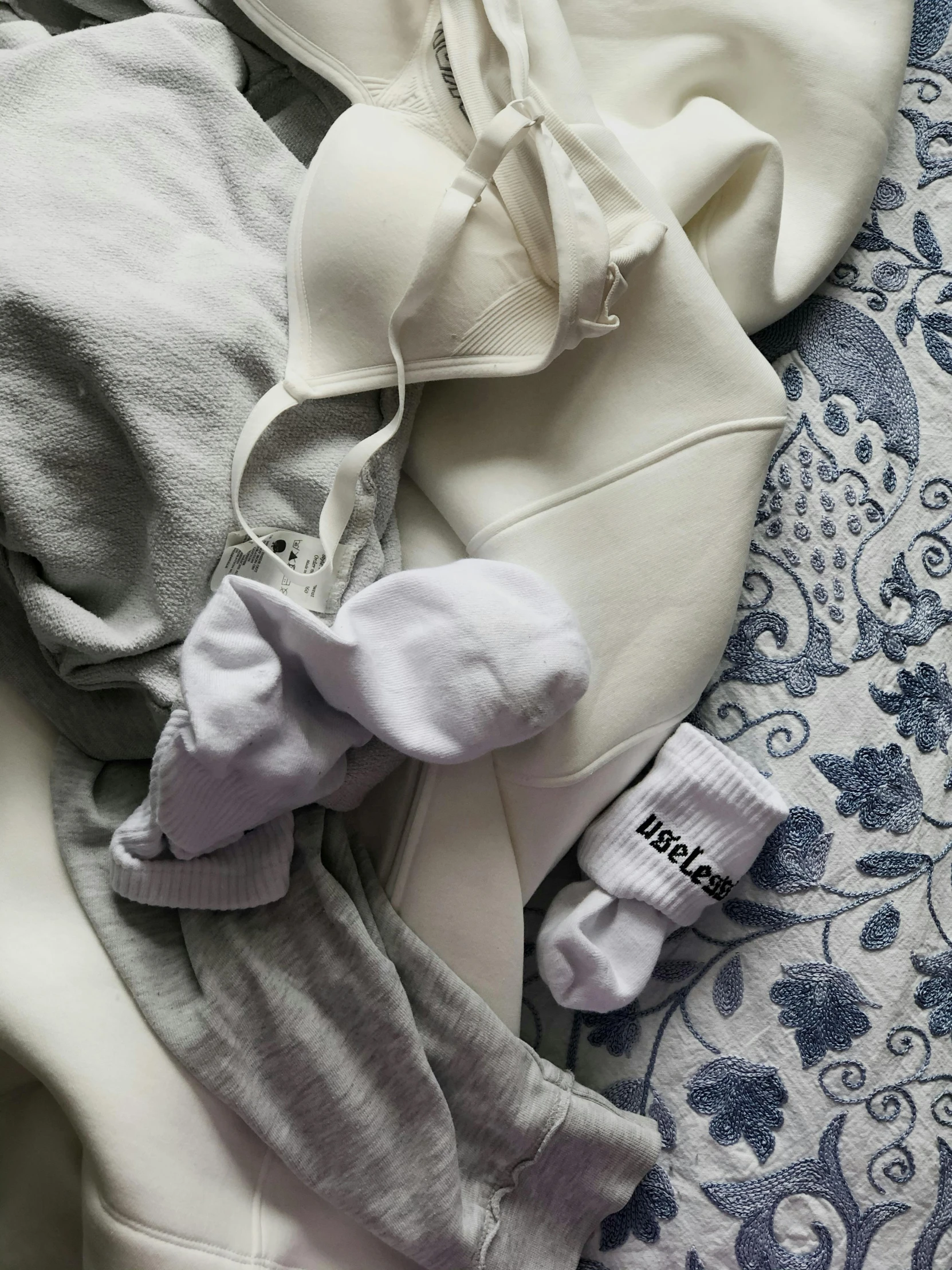 a pile of clothes sitting on top of a bed, in white lettering, white grey color palette, ((oversaturated)), white gloves