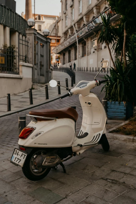 a motor scooter parked on a cobblestone street, cream and white color scheme, 🚿🗝📝, 1 2 9 7, nice lighting