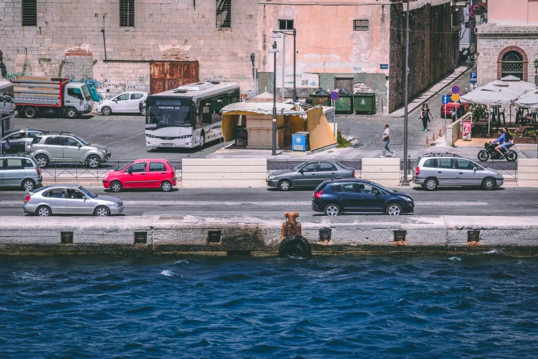 a city street filled with lots of traffic next to a body of water, a photo, pexels contest winner, renaissance, ignant, a car, indigo and venetian red, grey