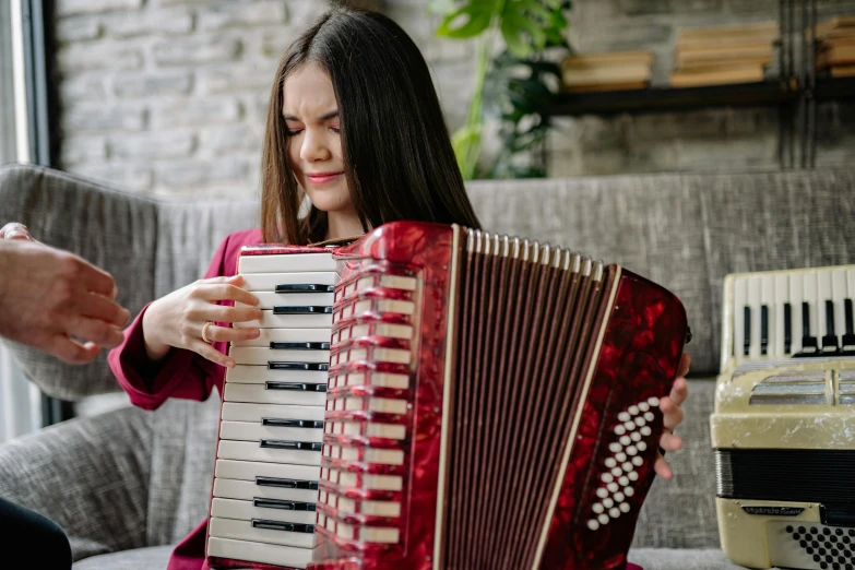 a little girl sitting on a couch playing an accordion, by Julia Pishtar, pexels contest winner, baroque, avatar image, woman, medium close up shot, promotional image