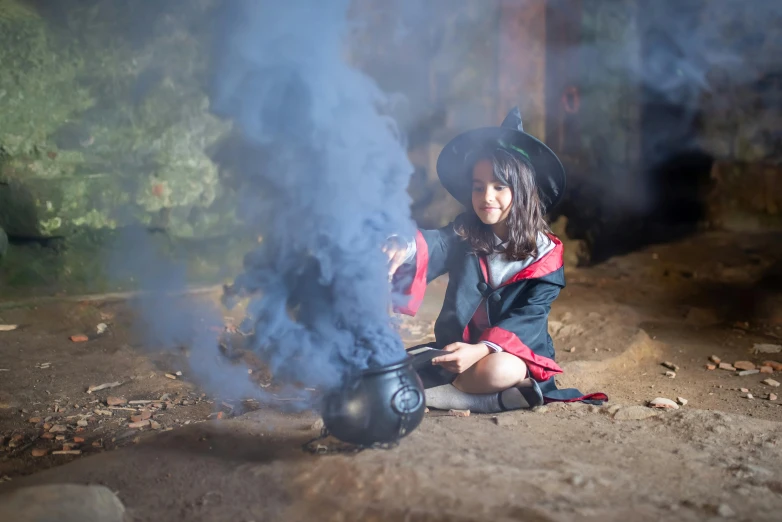 a woman sitting on the ground next to a pot with smoke coming out of it, wizard themed, magic school uniform, trick or treat, press shot