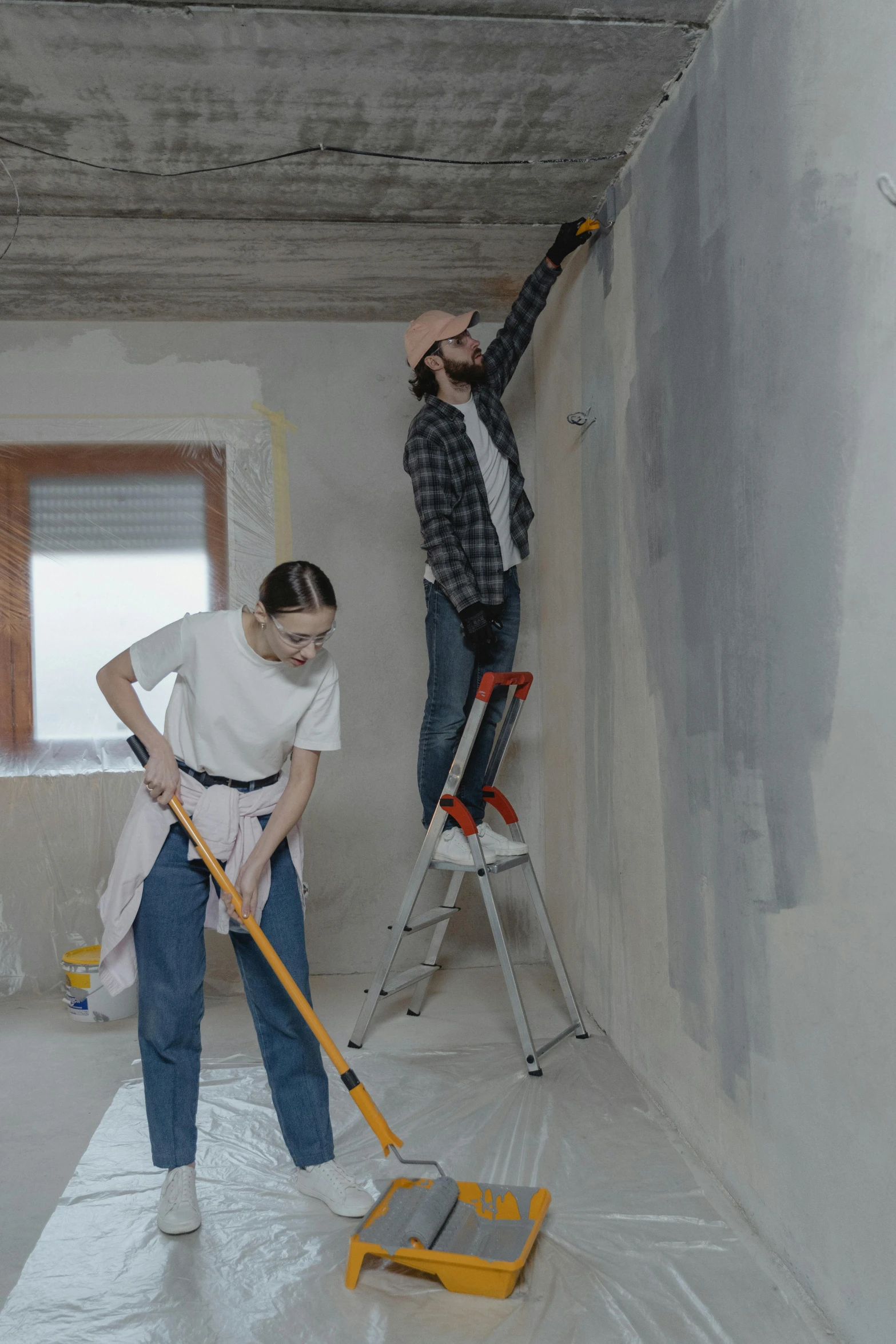 a couple of people that are standing on a ladder, a painting, trending on pexels, arbeitsrat für kunst, walls are made of dry wall, simple ceiling, thumbnail, low quality photo