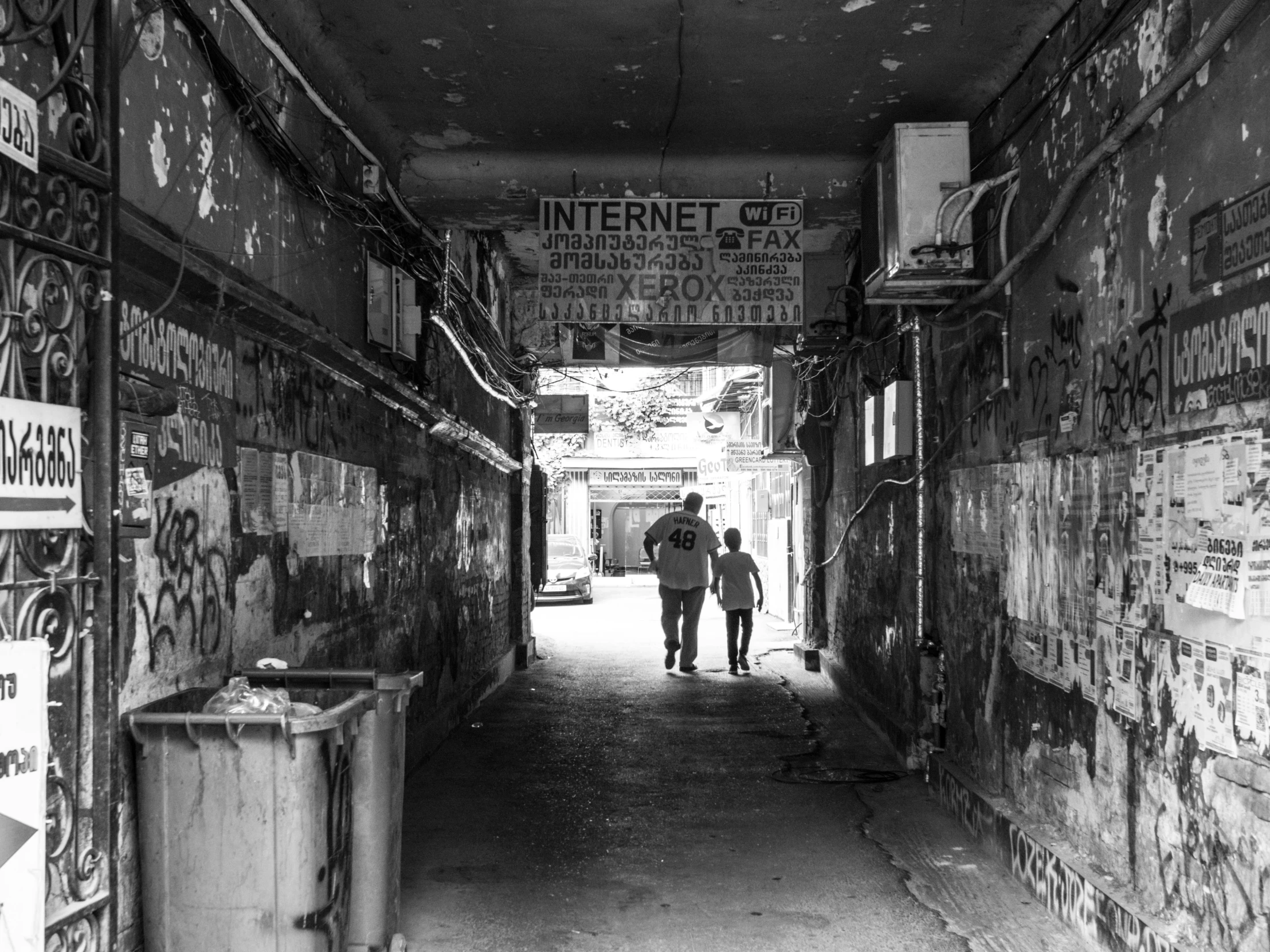 a black and white photo of two people walking down an alley, by Dennis Flanders, pexels, graffiti, in front of the internet, concrete hitech interior, in sci - fi mumbai, ruin