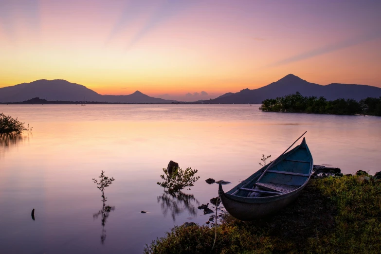 a boat sitting on the shore of a lake, by Aya Goda, pexels contest winner, volcano setting, vietnam, soft lilac skies, vibrant sunrise