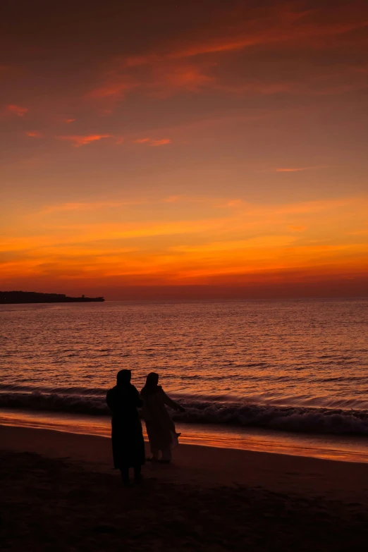 a couple of people standing on top of a beach, romanticism, jerez, ((sunset)), clad in robes, really long