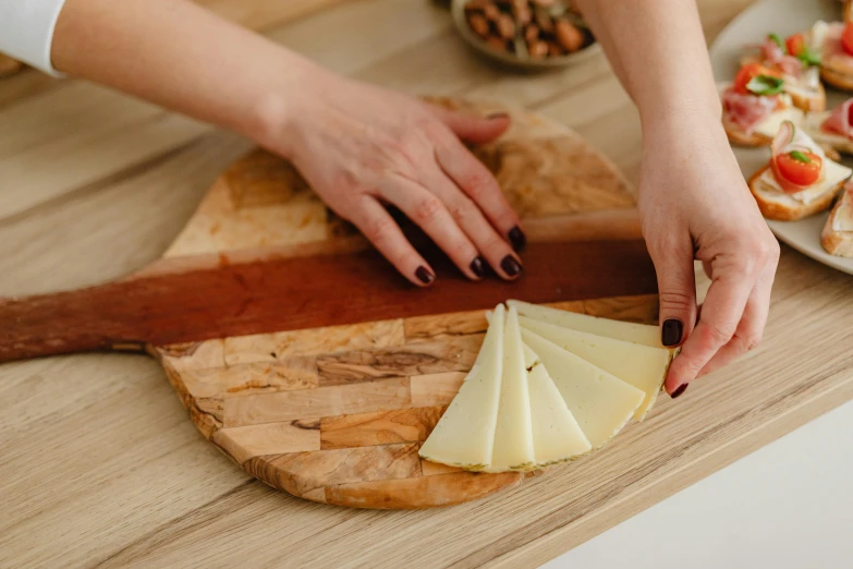 a close up of a person cutting cheese on a cutting board, by Julia Pishtar, hands pressed together in bow, nonagon infinity, chilean, various posed