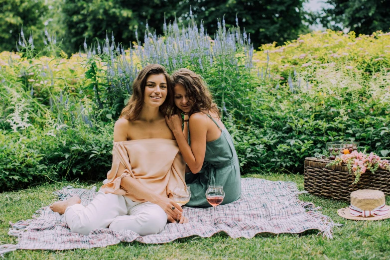 two women sitting on a blanket in the grass, a portrait, by Carey Morris, pexels, wine, sitting in the rose garden, julia sarda, posing for a picture