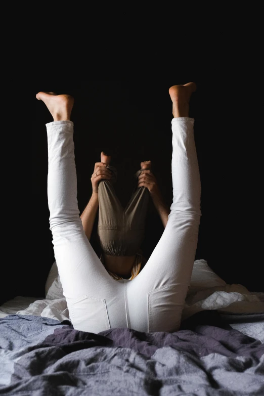 a woman laying on top of a bed next to a mirror, inspired by Sarah Lucas, pexels contest winner, arabesque, white leggings, standing with a black background, his legs spread apart, yoga pose