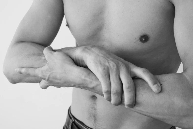 a black and white photo of a man holding his arm, a black and white photo, inspired by Robert Mapplethorpe, unsplash, hyperrealism, belly button showing, ignant, holding an epée, kai carpenter