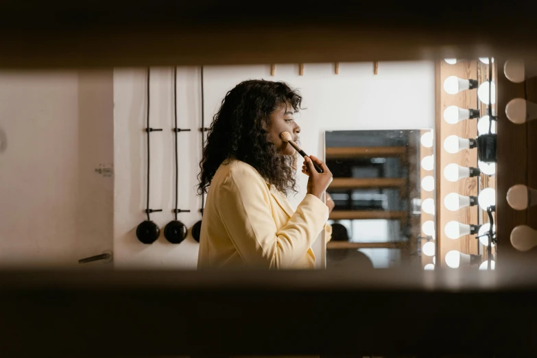 a woman brushing her teeth in front of a mirror, pexels contest winner, happening, brown skin. light makeup, profile image, with yellow cloths, mysterious coffee shop girl