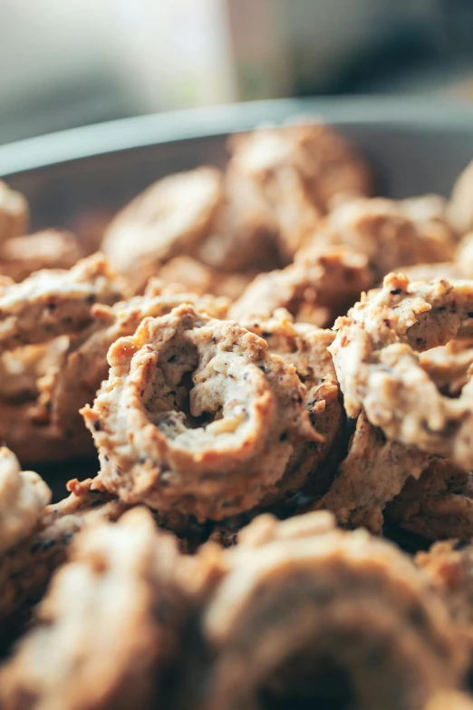 a bowl full of cookies sitting on top of a table, by Jan Tengnagel, unsplash, baroque, cow horns, blurred detail, in the shape of a cinnamon roll, many holes