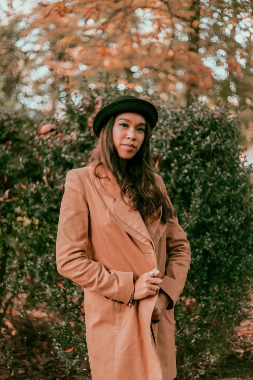 a woman in a coat and hat posing for a picture, an album cover, by Dulah Marie Evans, wearing brown leather jacket, trees in the background, jordan lamarre - wan, profile image