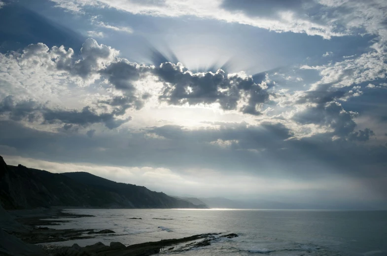 the sun shines through the clouds over the ocean, a picture, inspired by Richard Wilson, nadav kander, god light shafts, south african coast, looking towards camera