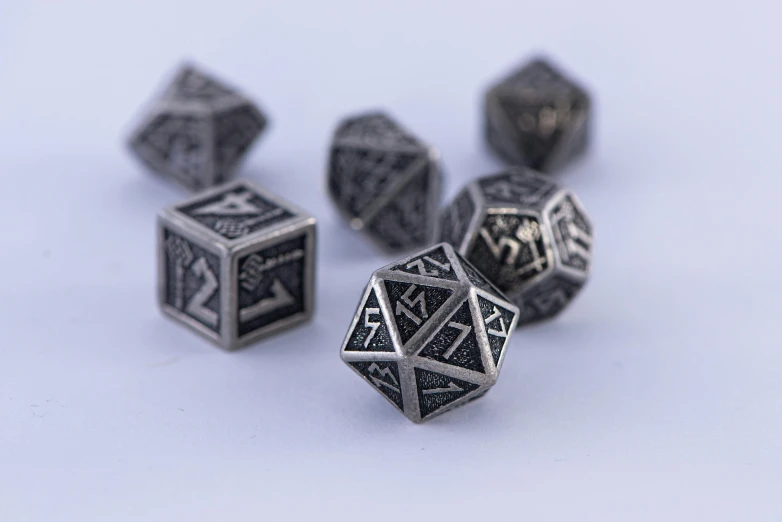 a bunch of metal dice sitting on top of a table, an engraving, geometric, [ metal ], silver insignia, thumbnail