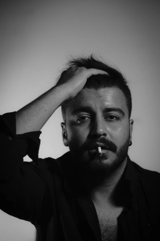 a black and white photo of a man smoking a cigarette, an album cover, by Nabil Kanso, small beard, aykut aydogdu, matteo salvini, taken in the early 2020s