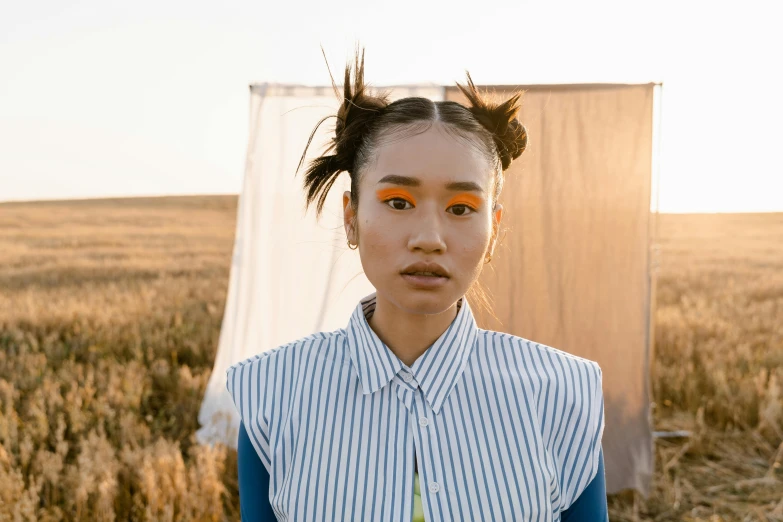 a woman standing in the middle of a field, an album cover, inspired by Kim Tschang Yeul, unsplash, two pigtails hairstyle, ashteroth, frown fashion model, evening light