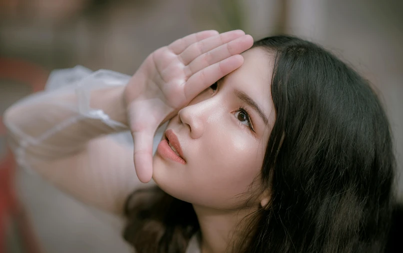 a woman holding her hands up to her face, trending on pexels, hyperrealism, square face, asian girl, glossy eyes, low angle photograph