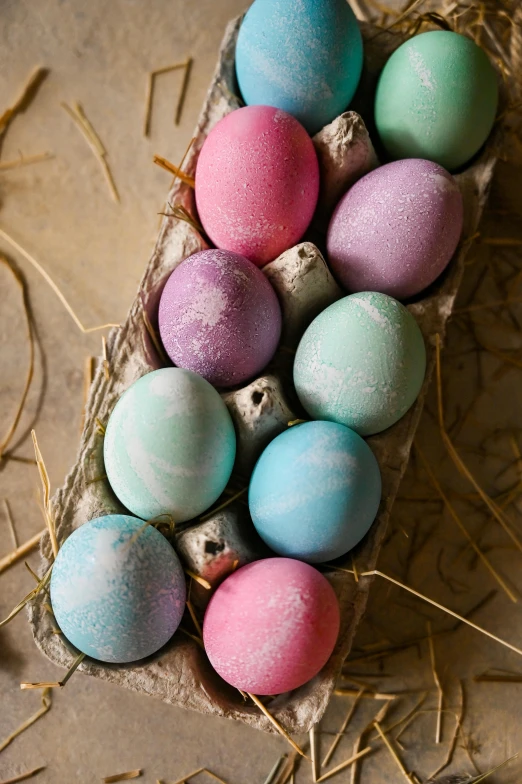 a carton filled with eggs sitting on top of hay, a pastel, colored marble, pink and blue and green mist, chalked, marbled swirls