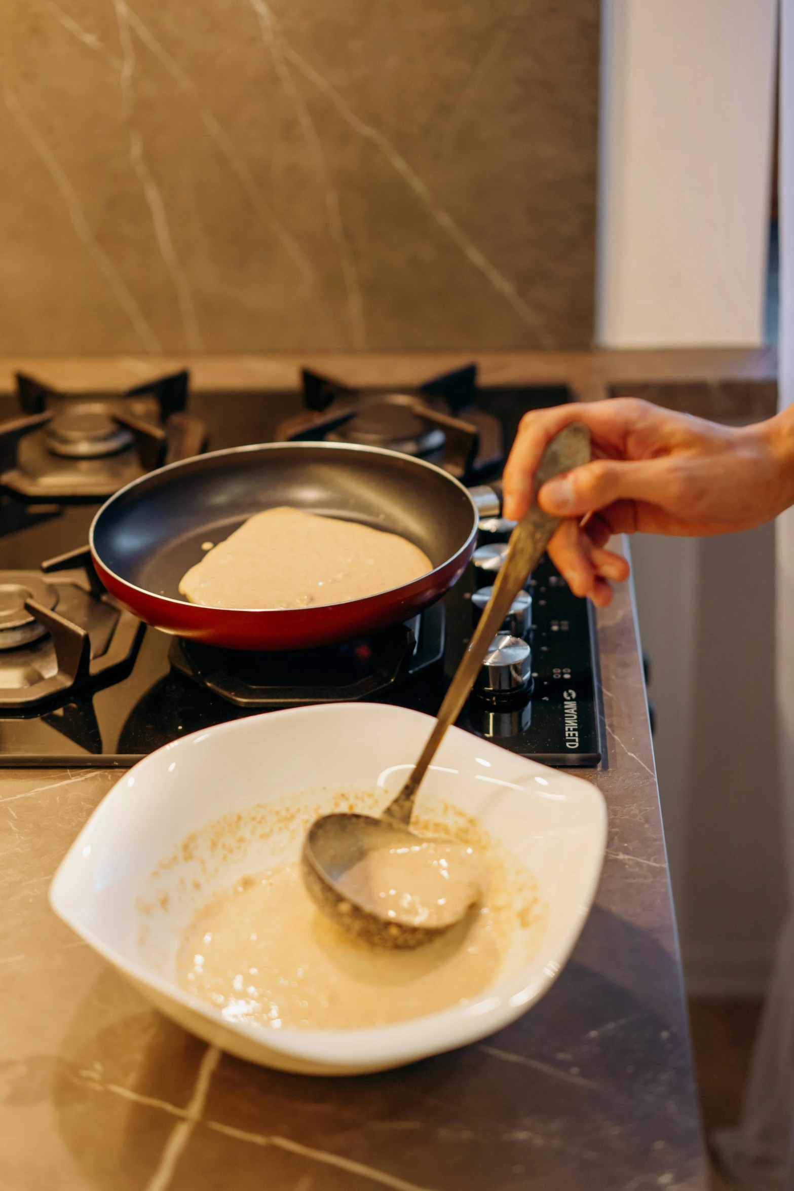 a person stirring something in a bowl on a stove, pancake flat head, square, liquid gold, no cropping