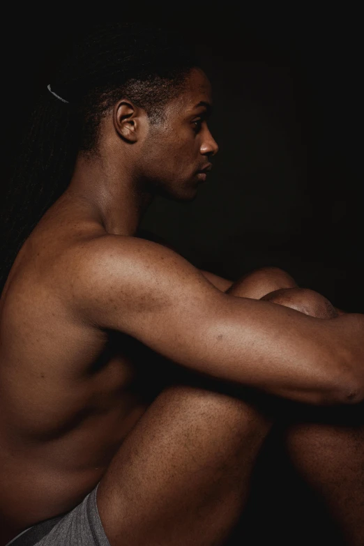 a man sitting on the ground with his legs crossed, an album cover, by Robert Mapplethorpe, pexels contest winner, renaissance, ( ( dark skin ) ), rear side portrait of a muscular, contemplating, embracing
