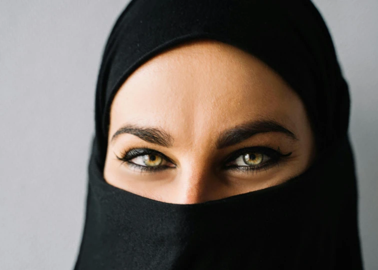 a woman wearing a black veil covering her face, an album cover, inspired by Modest Urgell, trending on unsplash, hurufiyya, identical eyes, arabian wrestling woman, looking straight into camera, friendly eyes