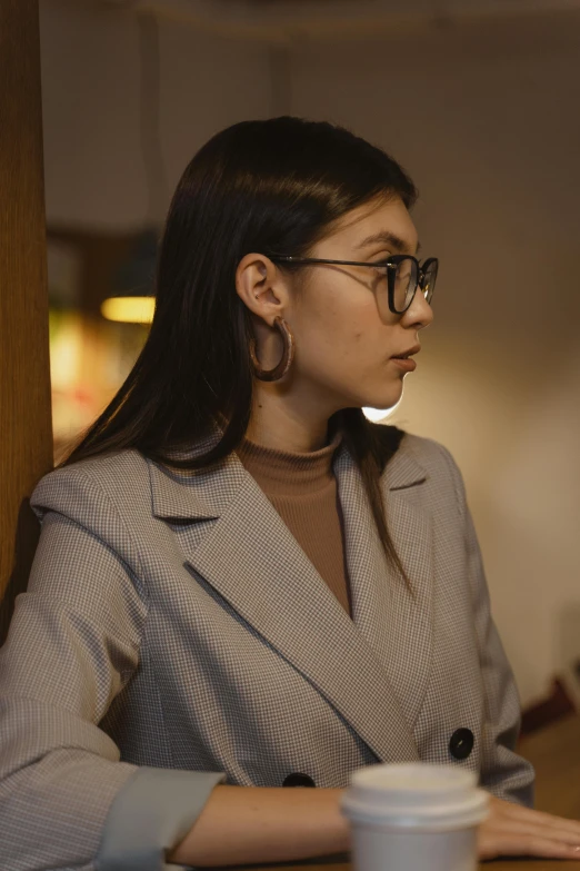 a woman sitting at a table using a laptop computer, a character portrait, trending on pexels, wearing a suit and glasses, moody lighting, young asian woman, grey turtleneck coat