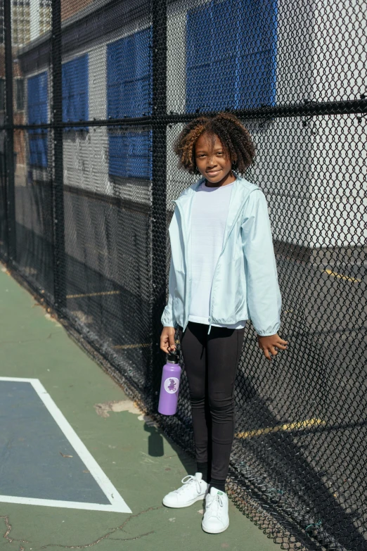 a little girl standing on a tennis court holding a tennis racquet, pexels contest winner, graffiti, wearing a purple sweatsuit, full body potrait holding bottle, african american girl, with a whitish