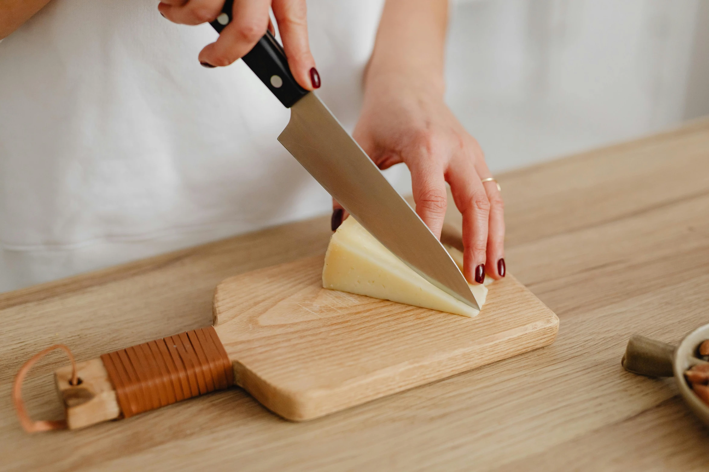 a person cutting a piece of cheese on a cutting board, inspired by Wilhelm Hammershøi, unsplash, striking pose, rebecca sugar, pine wood, looking towards camera