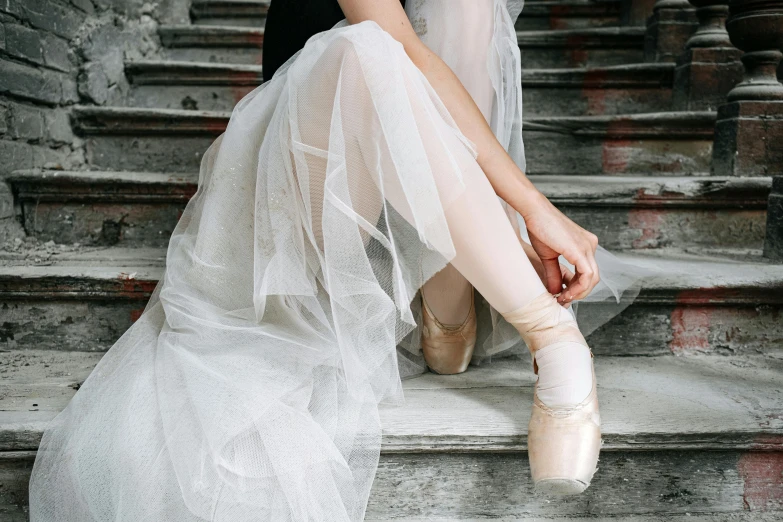 a woman in a white dress is sitting on some steps, by Elizabeth Polunin, pexels contest winner, arabesque, silver，ivory, tights, unfinished, dressed in a beautiful