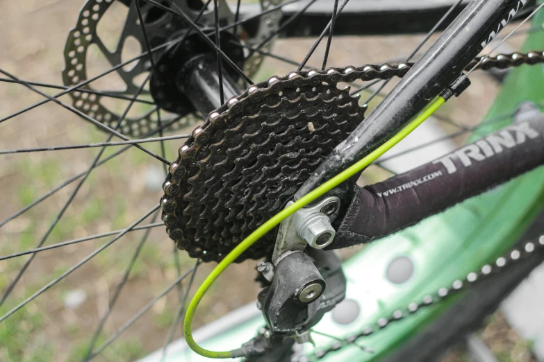 a close up of the rear end of a bicycle, ((gears)), black and green, chain mail, snacks